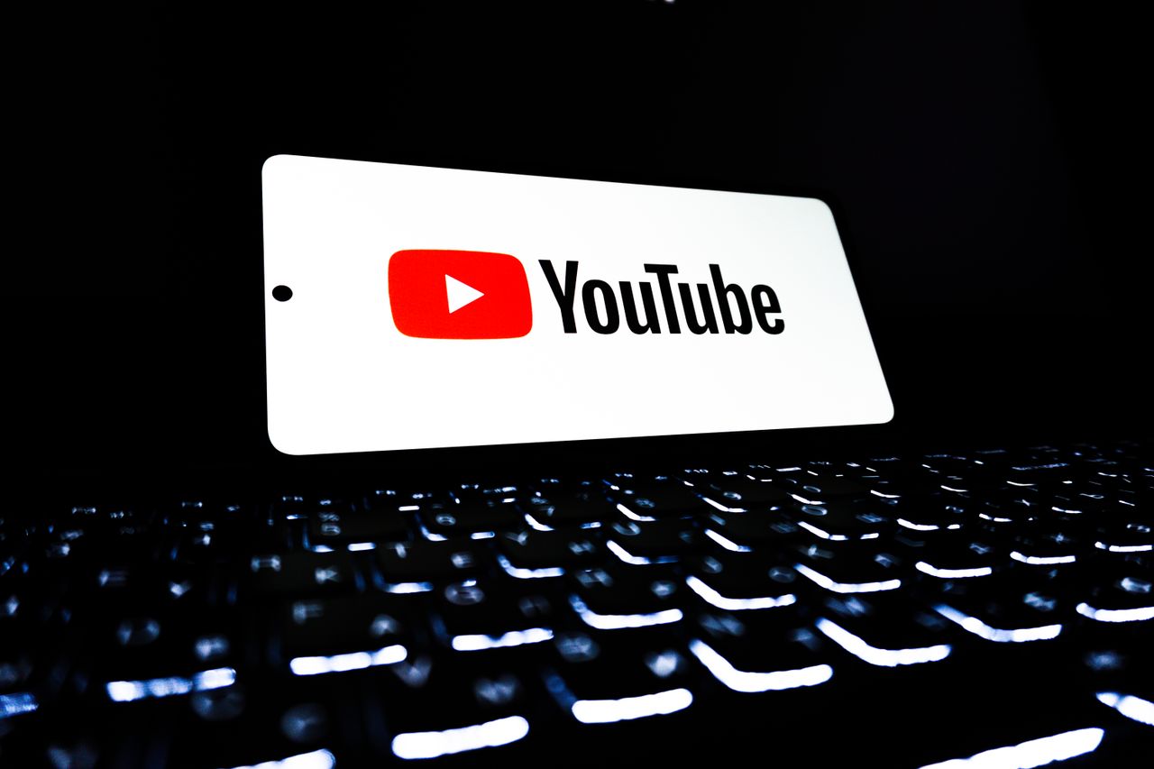 services-02 YouTube app icon displayed on a smartphone over an illuminated keyboard, representing digital media and online streaming.